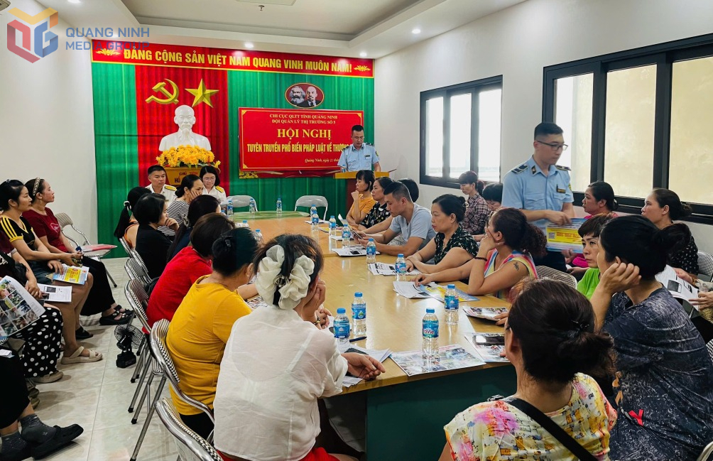 Đại diện Đội QLTT số 5 tuyên truyền pháp luật, phát tờ rơi cho các hộ kinh doanh tại chợ Hạ Long II. Ảnh: Ngọc Trâm